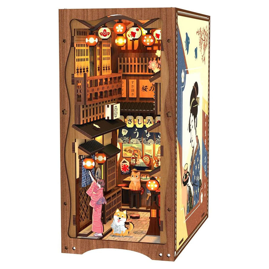 Under the Sakura Tree Book Nook (PREORDER) - Wooden book nook diorama of a Japanese street scene under cherry blossoms with lanterns and a woman in a pink kimono with a.
