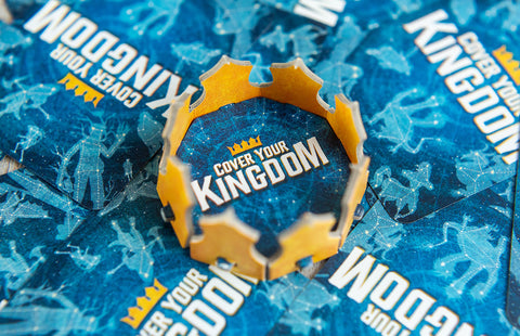 Cover Your Kingdom - Gold crown-shaped card holder on blue cards with white "Cover Your Kingdom" text and star patterns.