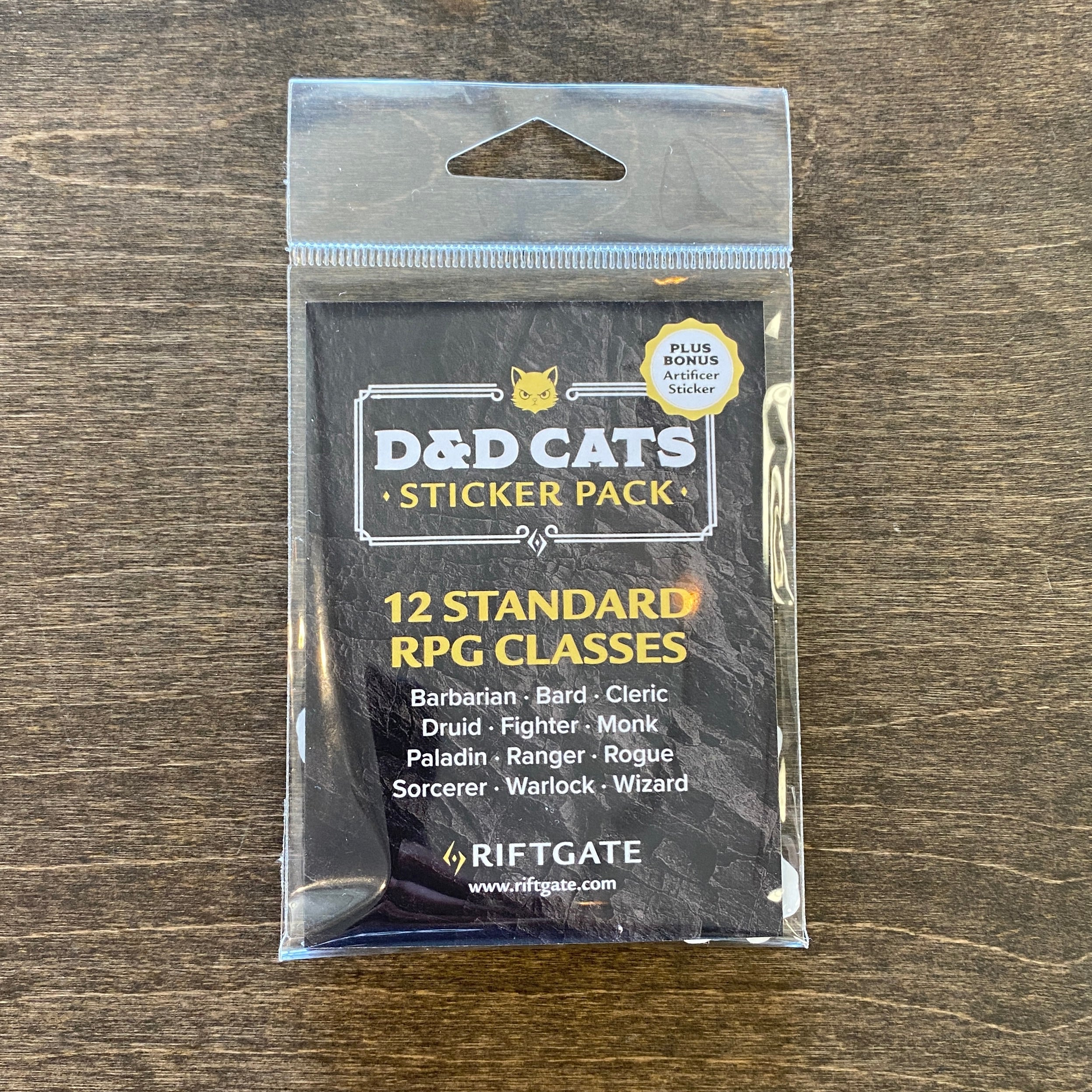 D&D Cat Sticker Pack - Black and white packaged D&D Cats Sticker Pack with 12 RPG class stickers by Riftgate on wooden background.