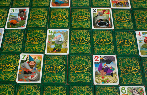 Gnoming A Round - Gnoming A Round card game with green card backs featuring gold intricate designs and colorful gnome illustrations on face.