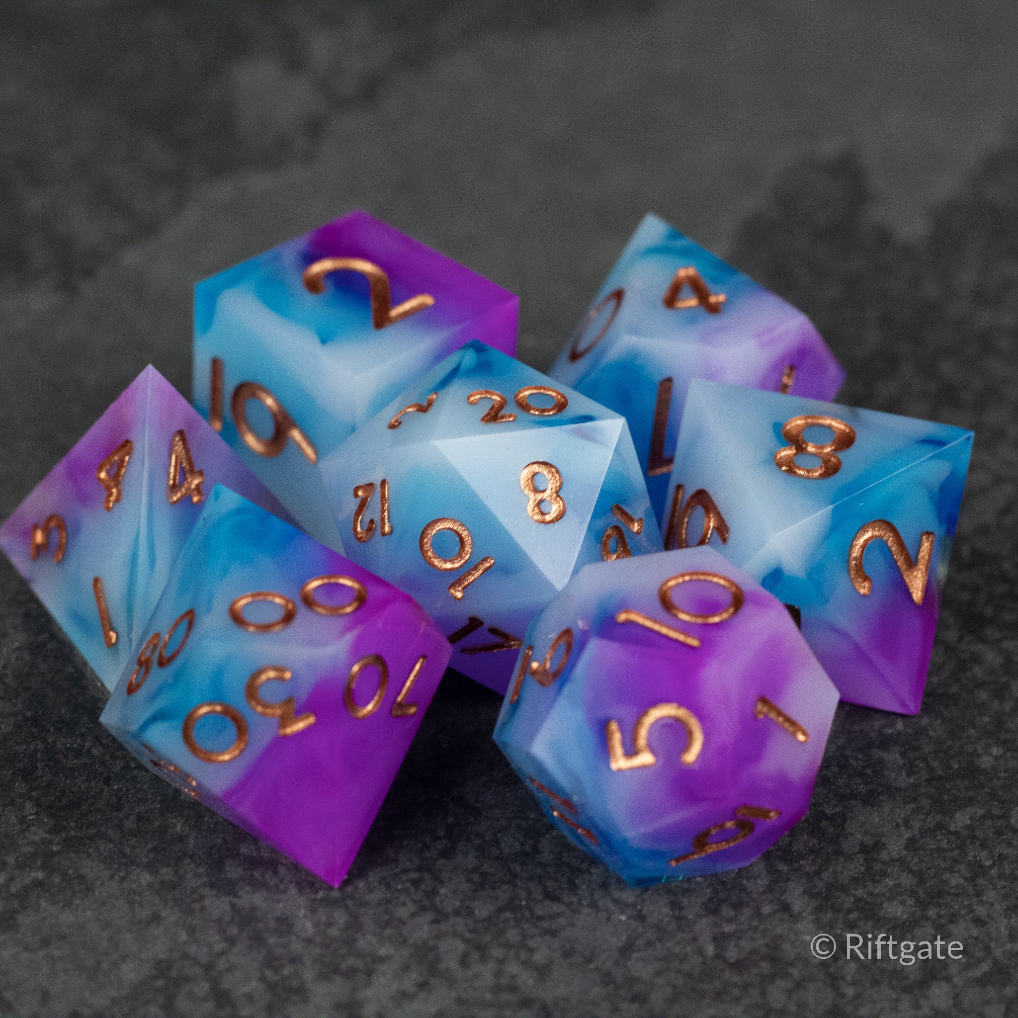 Arcane Tempest Dice Set - Purple and blue marbled sharp edge dice set with copper numbering on dark background.