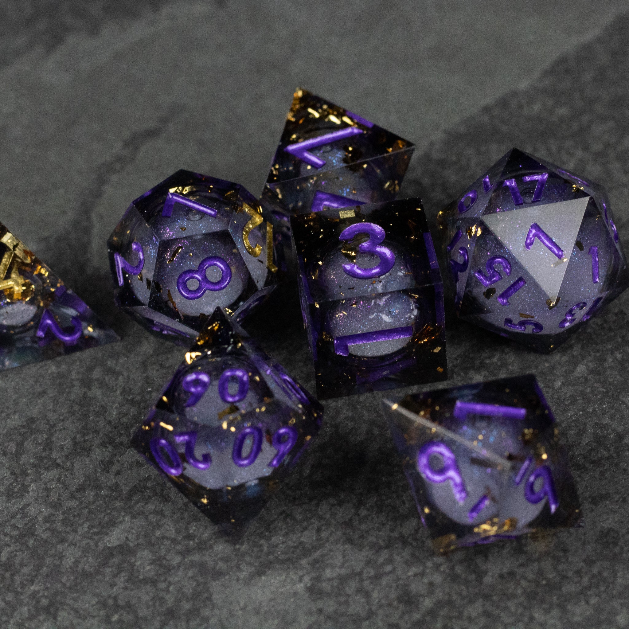 Witching Hour Liquid Core Dice - Black and purple sharp-edged polyhedral dice with translucent liquid core and gold flakes.