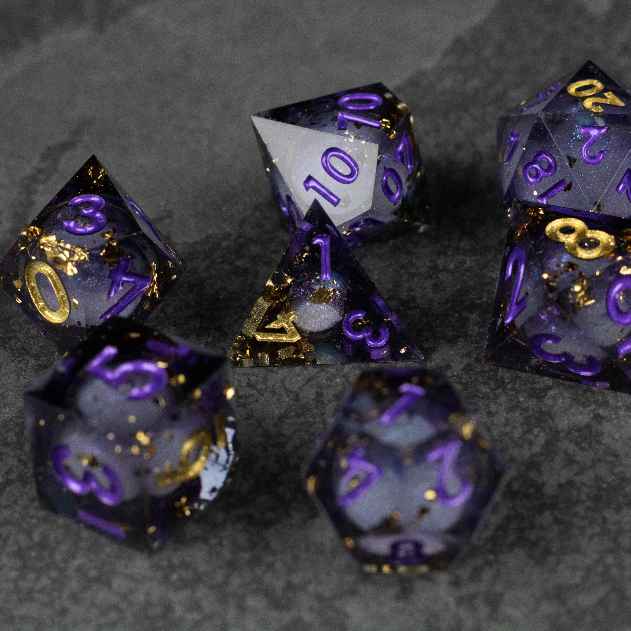 Witching Hour Liquid Core Dice - Set of seven sharp-edged polyhedral dice with a translucent black and purple liquid core, featuring gold and purple.