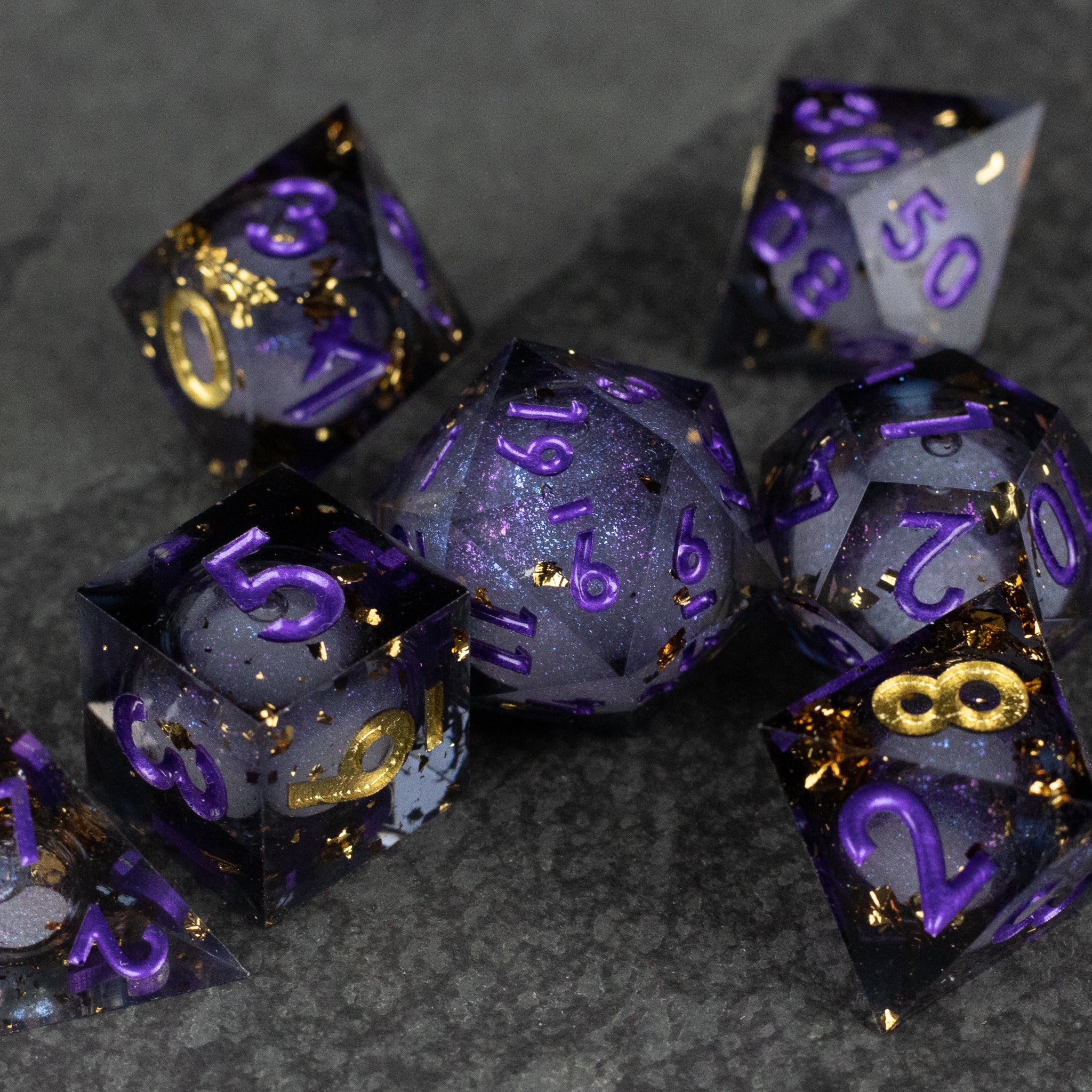Witching Hour Liquid Core Dice - Set of seven sharp-edged polyhedral dice with translucent purple liquid cores and gold flecks, purple numbering on black.