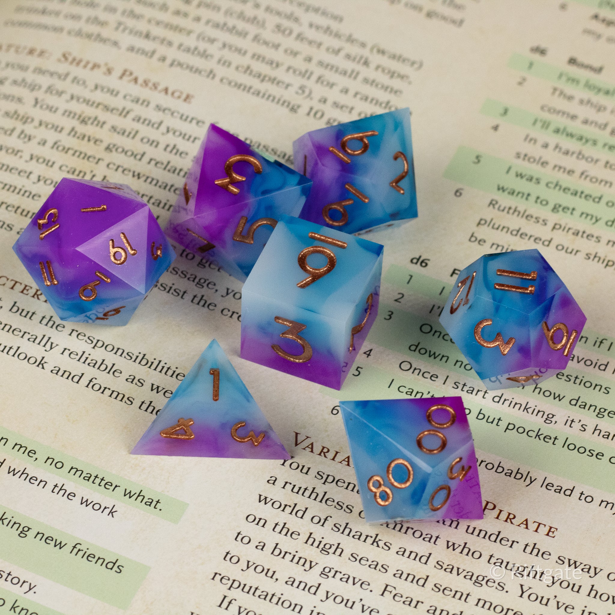 Arcane Tempest Dice Set - Colorful translucent polyhedral dice set in blue, purple, and white with gold numbering on a book page.