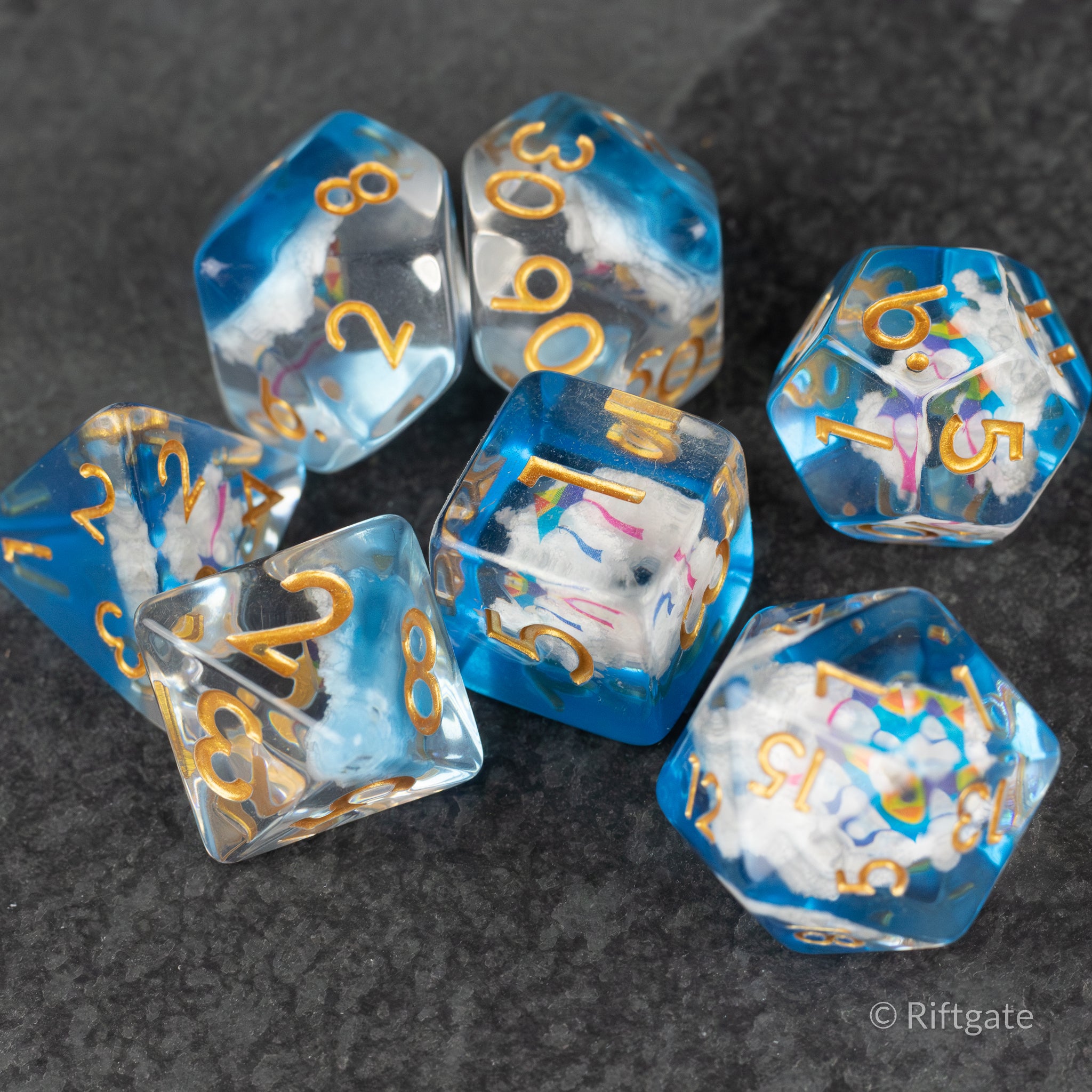 Clouds & Kites Dice - Set of six polyhedral dice with blue and white cloudy swirls and gold numbers on a dark surface.