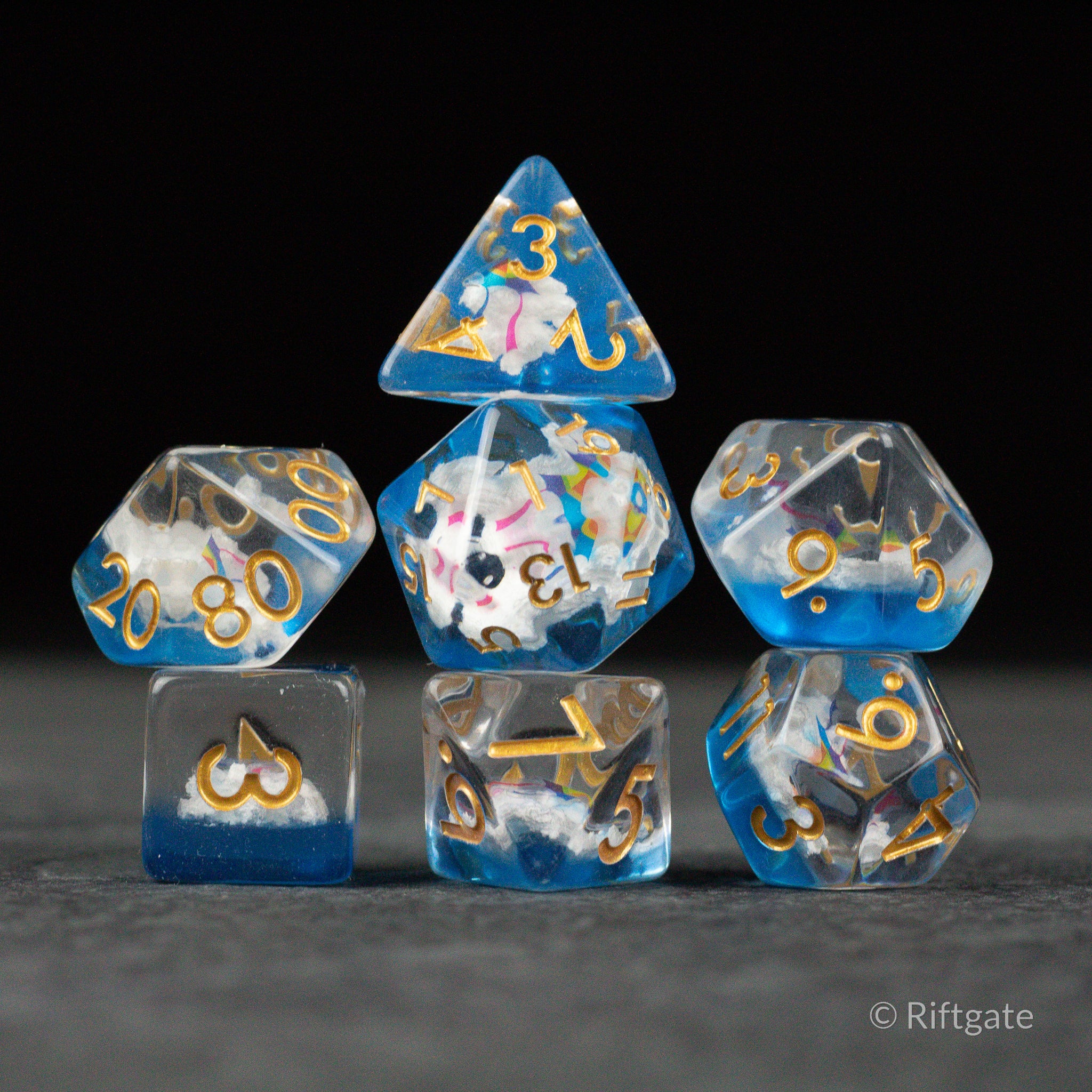 Clouds & Kites Dice - Set of seven translucent polyhedral dice with swirling blue, white, and yellow cloud and kite patterns, gold numbering.
