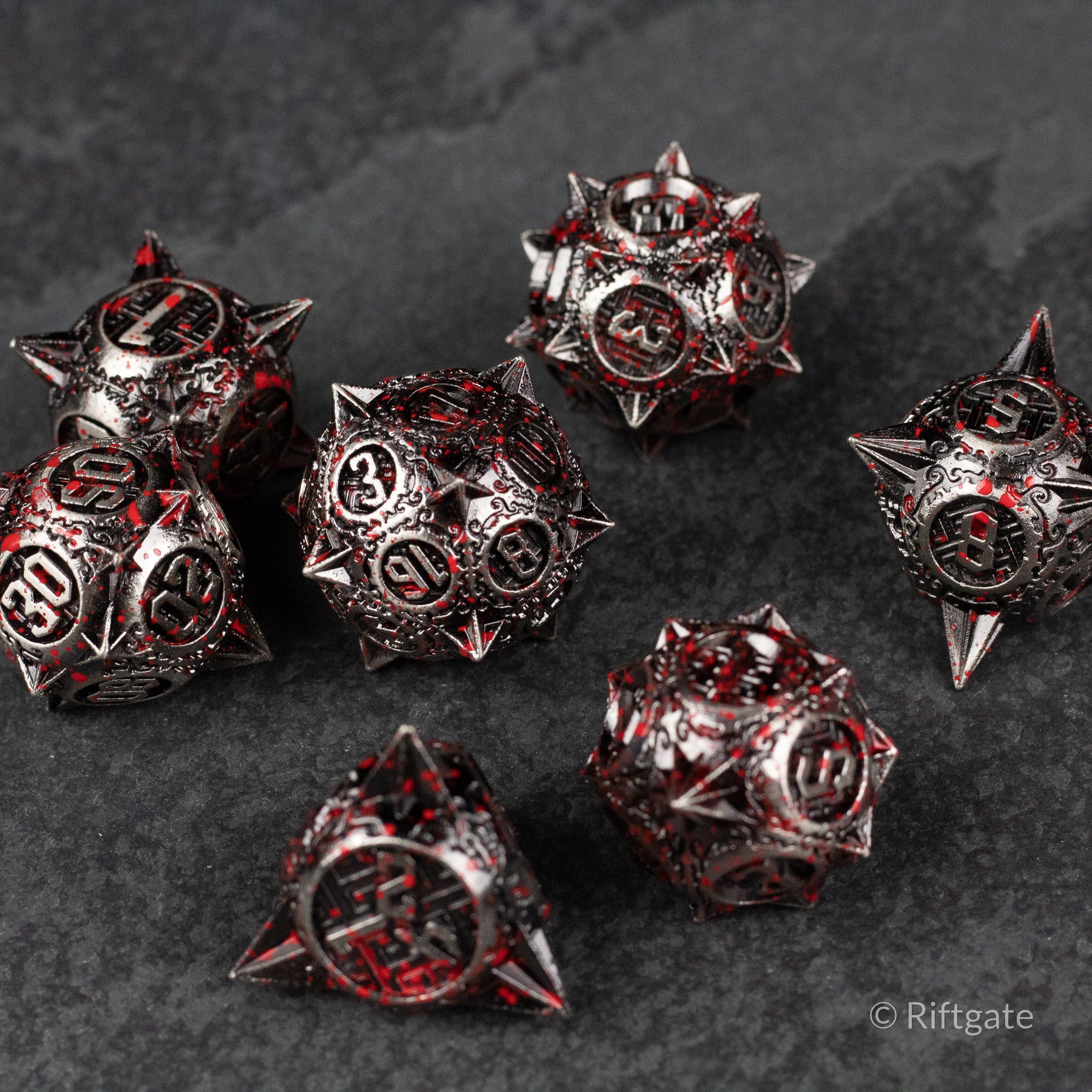 Bloody Morning Star Metal Dice Set - Metal RPG dice set with blood red accents, featuring spiked d20, d12, d10, d8, d6, and d4 designs on dark surface.