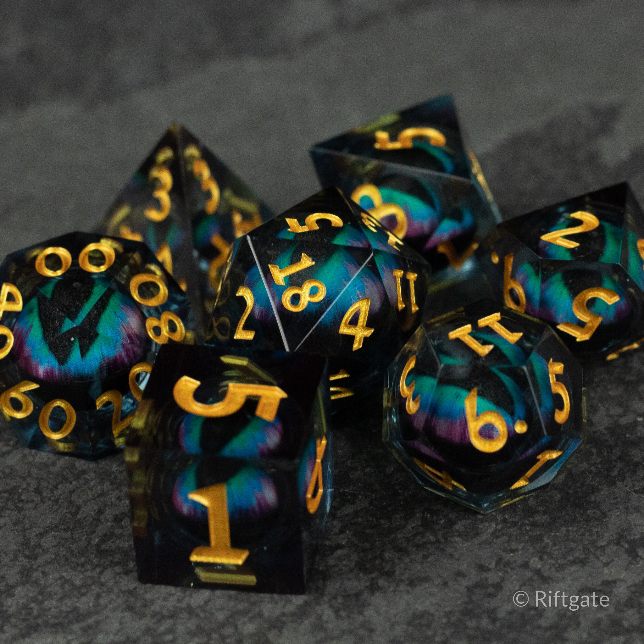 Cosmic Beholder's Eye Dice Set - Black and teal d20 dice set with gold numbers and eye-like liquid core design.