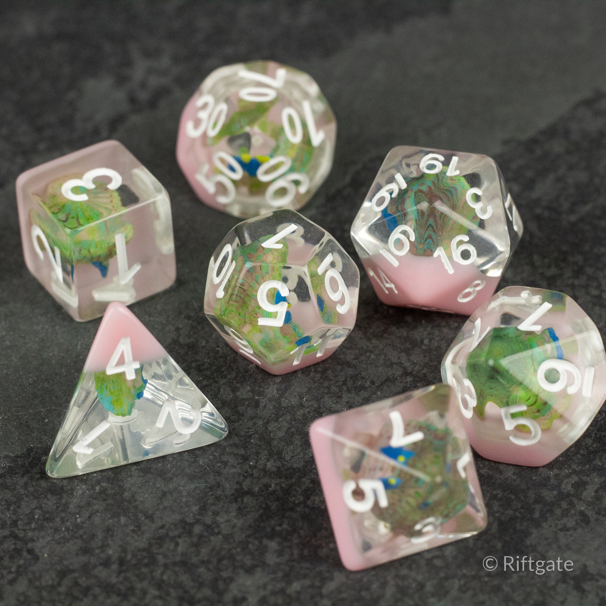 Peacock Dice Set - Set of seven translucent polyhedral dice with pink edges and white numbers, featuring colorful peacock feather designs.