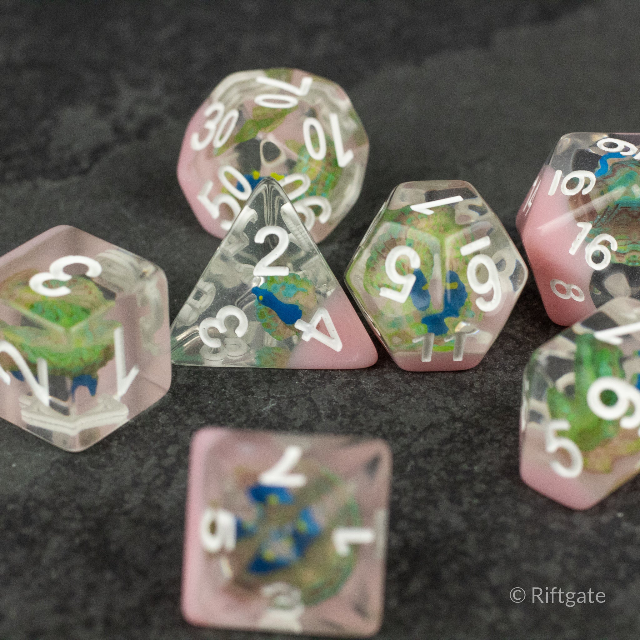 Peacock Dice Set - Set of six translucent pink polyhedral dice with colorful peacock feather inclusions and white numbering.