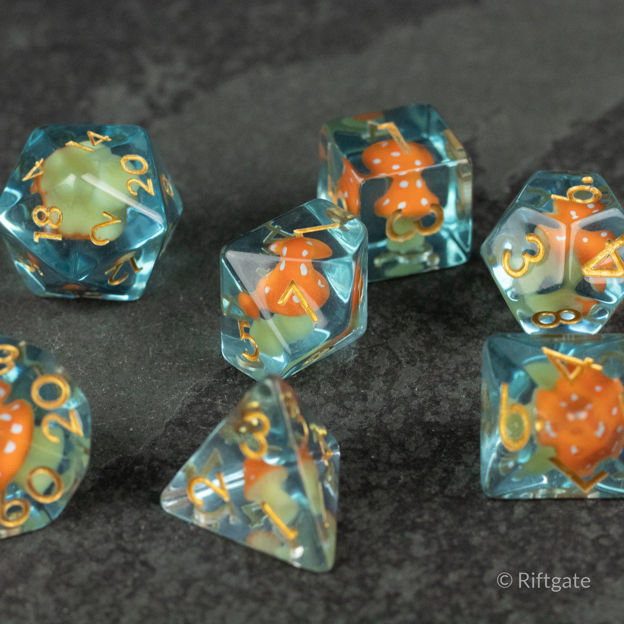 Orange + Blue Resin Mushroom Dice Set - Seven-piece translucent blue resin dice set with embedded orange mushroom inclusions and gold numbering.