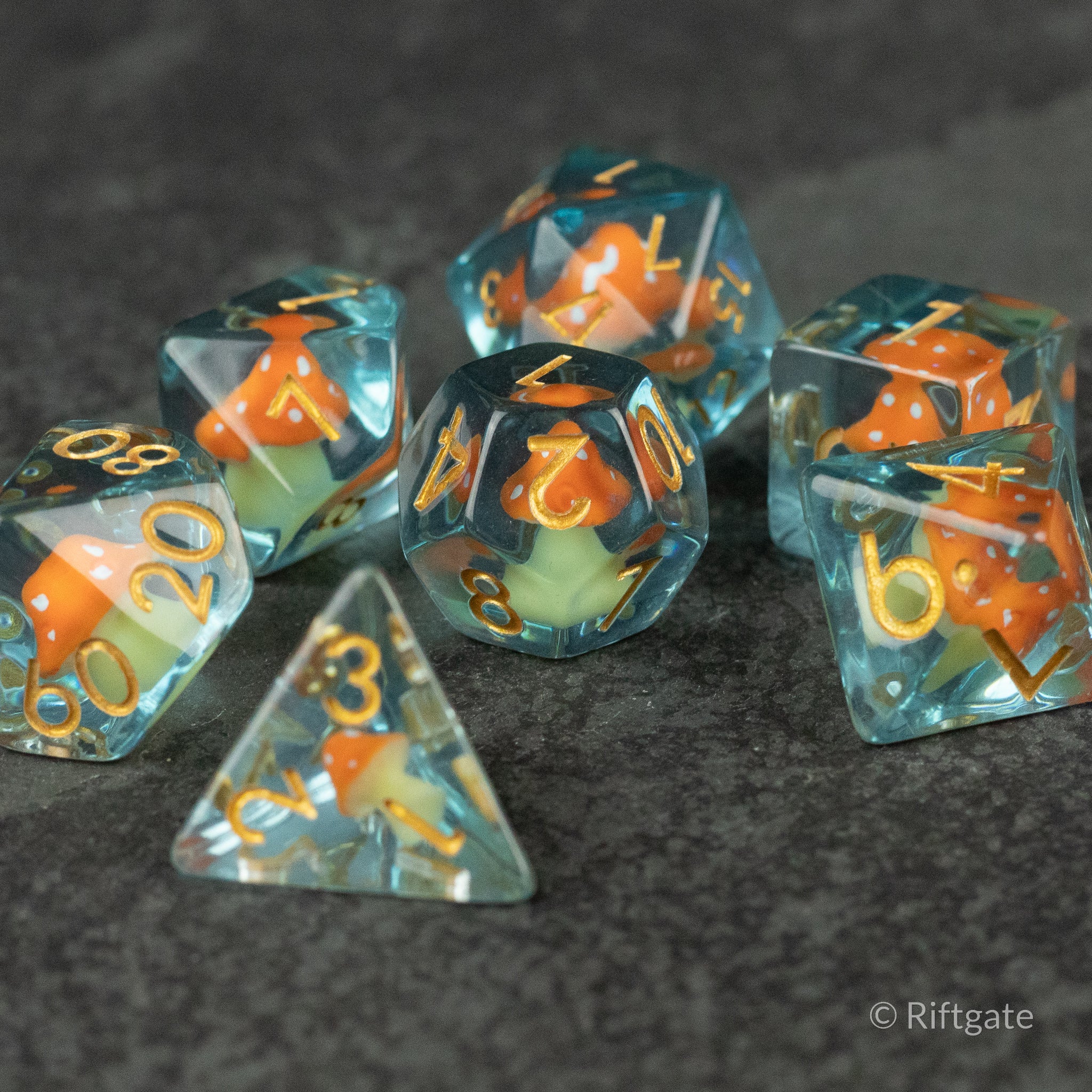 Orange + Blue Resin Mushroom Dice Set - Set of six transparent resin dice with orange and blue mushroom inclusions, gold numbering visible.