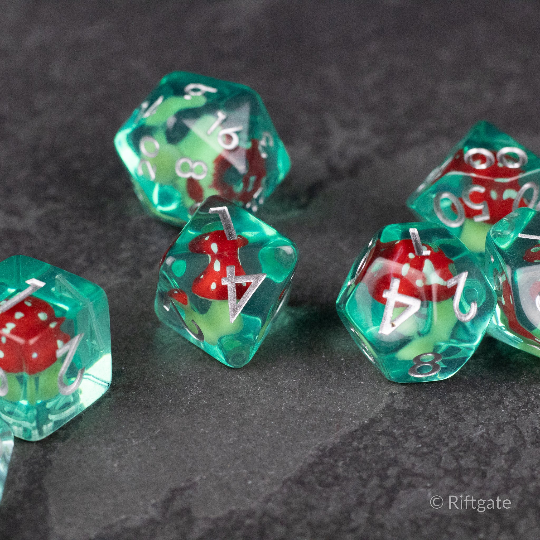 Red + Green Resin Mushroom Dice Set - Transparent green resin dice set with red mushroom inclusions and white numbers on each die.