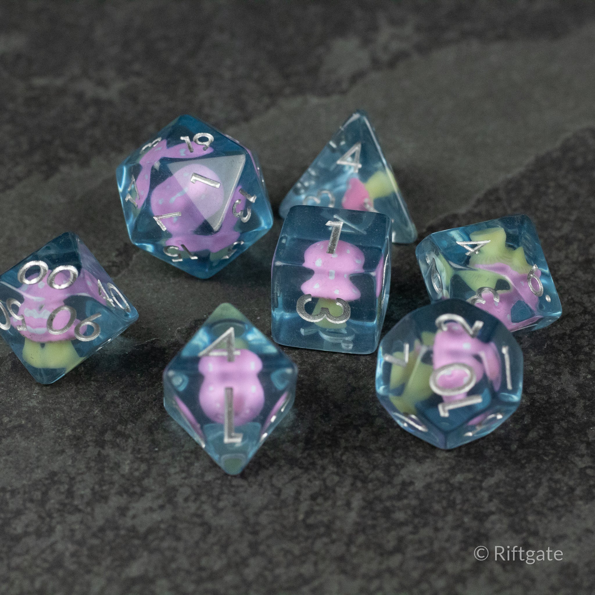 Pink + Blue Resin Mushroom Dice Set - Set of six translucent blue resin dice with pink mushroom and green plant inclusions.