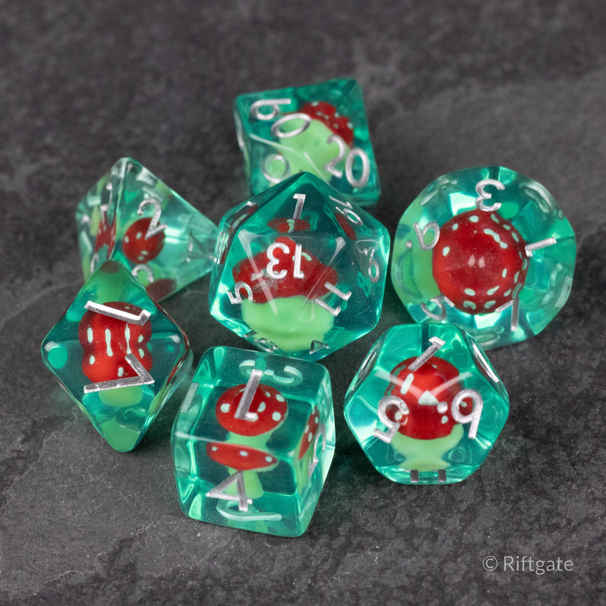 Red + Green Resin Mushroom Dice Set - Translucent teal resin dice set with red and green mushroom inclusions and white numbering.