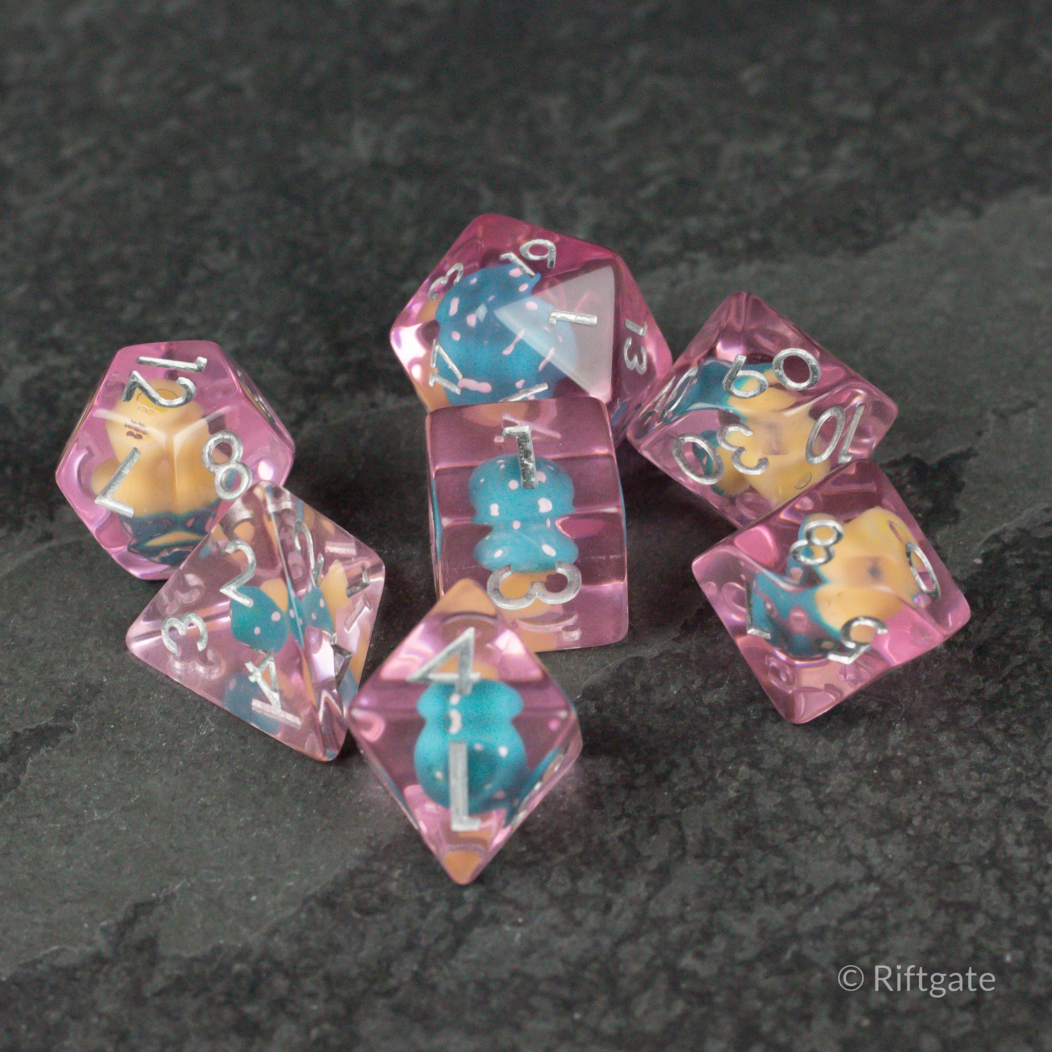 Blue + Pink Resin Mushroom Dice Set - Set of translucent pink resin dice with embedded blue and yellow mushroom inclusions, white numbering.