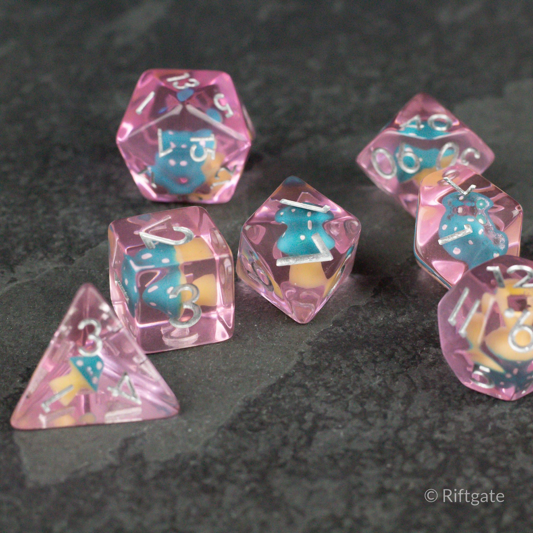 Blue + Pink Resin Mushroom Dice Set - Blue and pink resin polyhedral dice set with mushroom-shaped inclusions and white numbering on a dark surface.