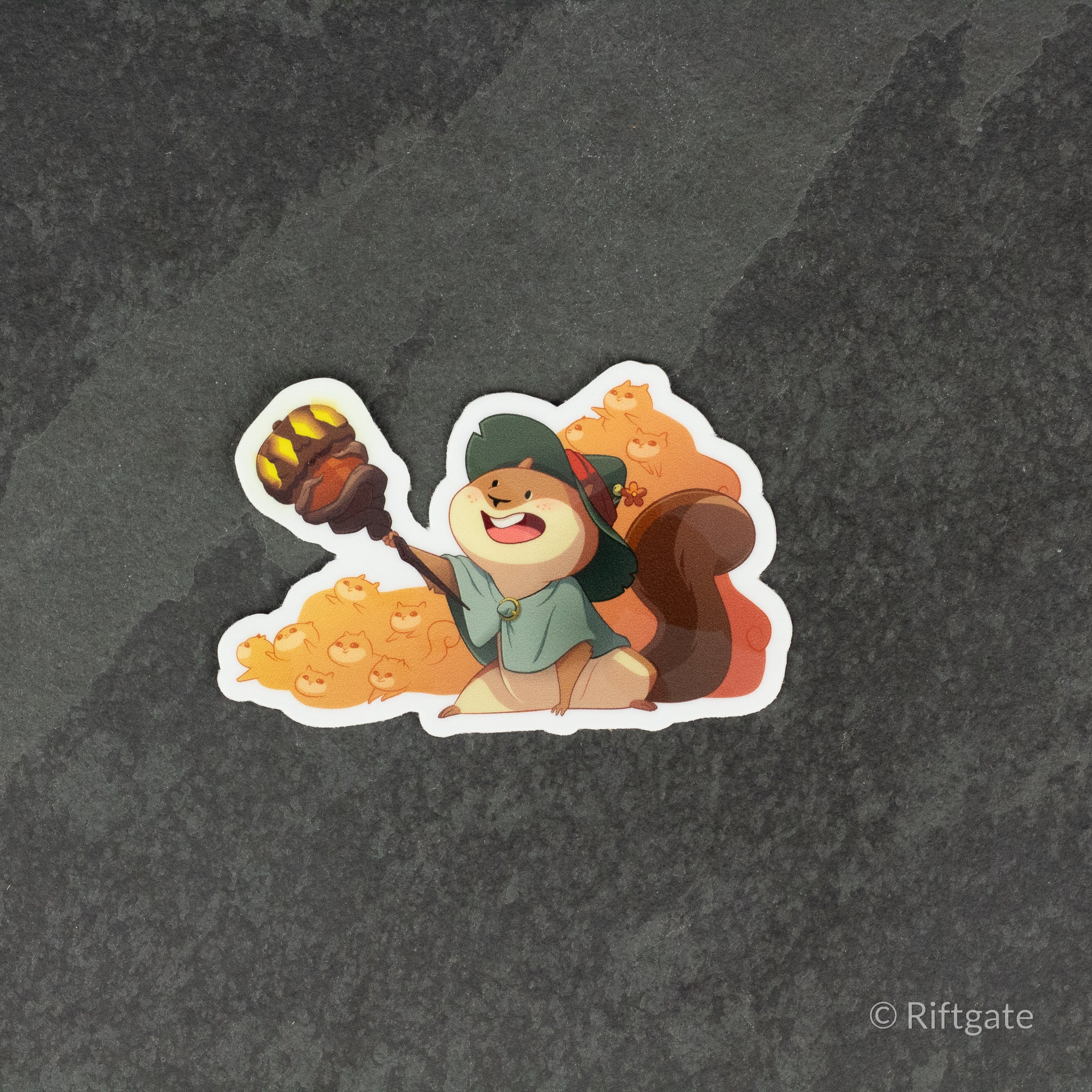 Squirrelmancer Sticker - Chibi squirrel wearing green hooded cloak holding glowing staff with large bushy tail sticker.