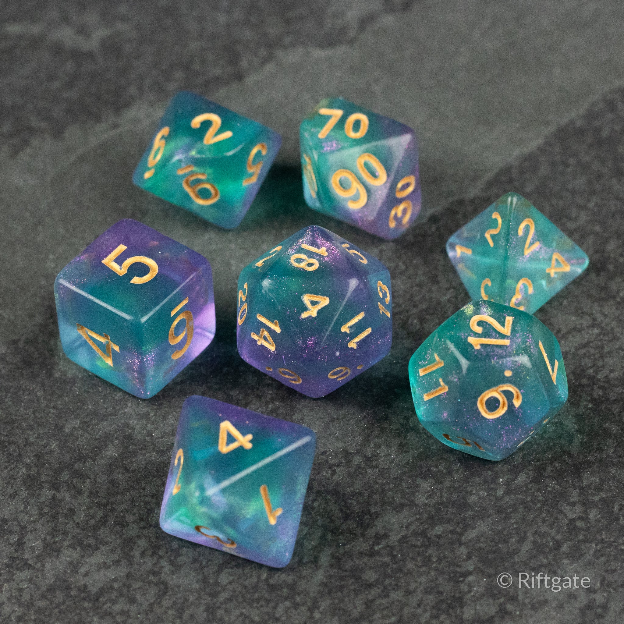 Faerie Glitter Dice Set - Set of seven translucent blue and purple polyhedral dice with gold numbers and glitter accents.