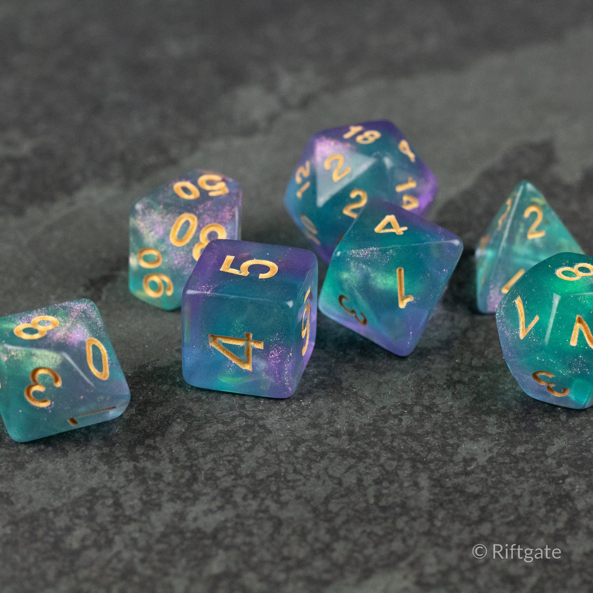 Faerie Glitter Dice Set - Set of seven translucent blue and purple polyhedral dice with gold numbers and glitter accents.