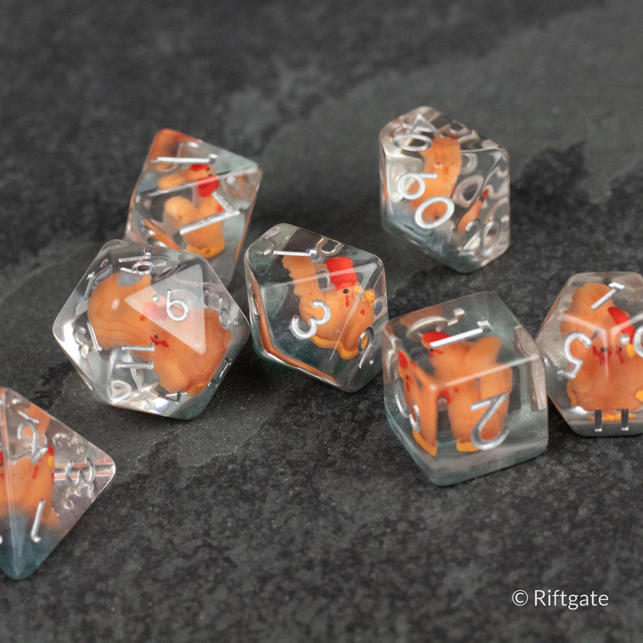 Chicken Dice Set - Set of seven clear polyhedral dice each with an orange and white chicken figure inside, featuring white numbers.