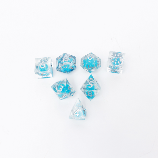 Cosmere RPG: Stormlight Deluxe Dice + Case (PREORDER) - Set of seven translucent blue polyhedral dice with white numbering, featuring a decorative storm-themed design on a plain.