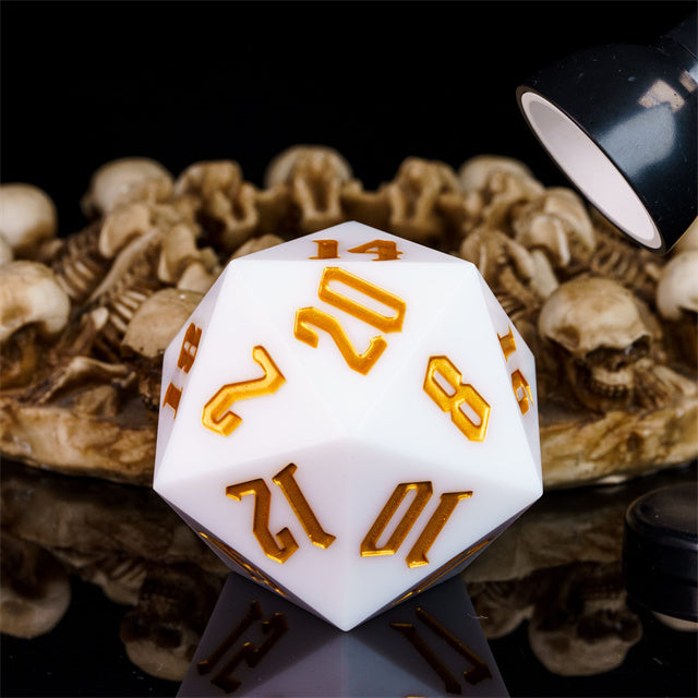 Giant 55mm D20 - White - Large white 20-sided acrylic dice with orange numbers, illuminated by a small black lamp.