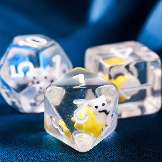 Snail Dice Set - Clear polyhedral dice with embedded white and yellow snail figures, white numbering on each face, displayed on blue fabric.