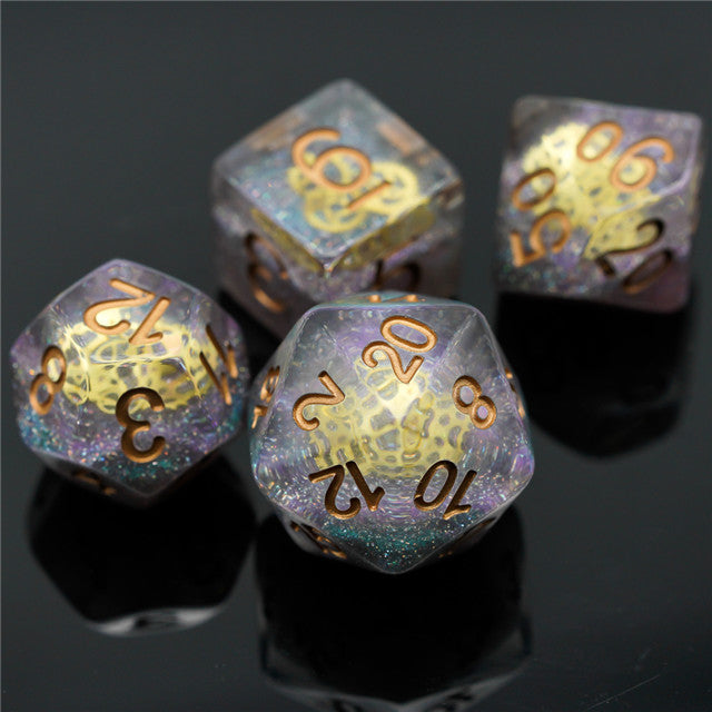 Mini Gears Dice Set - Transparent d20 dice set with rainbow glitter and gold numbers on a black reflective surface.