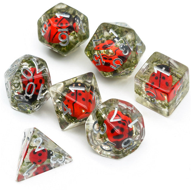 Ladybug Dice Set - Seven clear resin polyhedral dice with embedded red and black ladybug designs, including shapes like d20, d12, d10, d8, d6,.