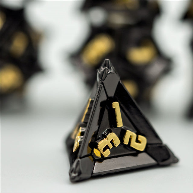 Caltrop Black Metal Dice Set - Black metal tetrahedron dice with gold numbers and sharp geometric edges.