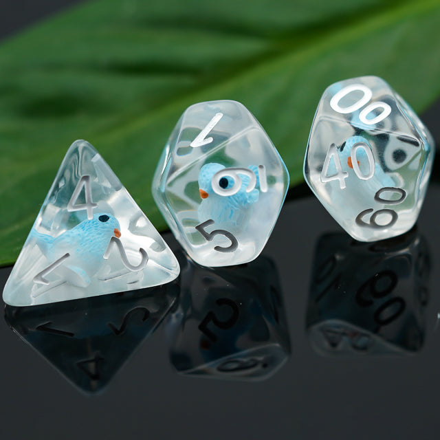 Blue Bird Dice Set - Transparent polyhedral dice set with blue bird illustrations and white numbers on reflective black surface.