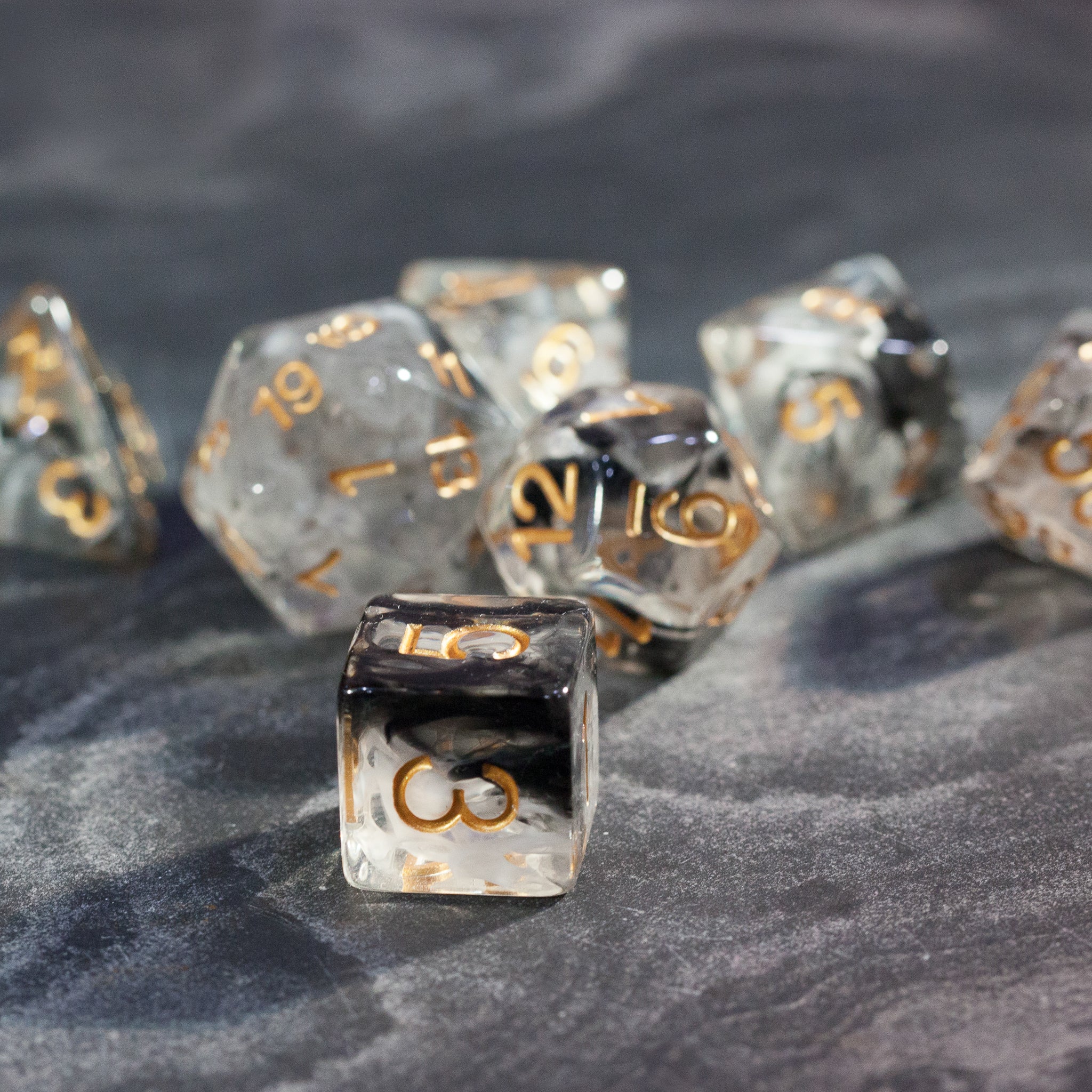 Black & White Smoke Dice Set - Set of translucent black and white smoke dice with gold numbers on a dark surface.