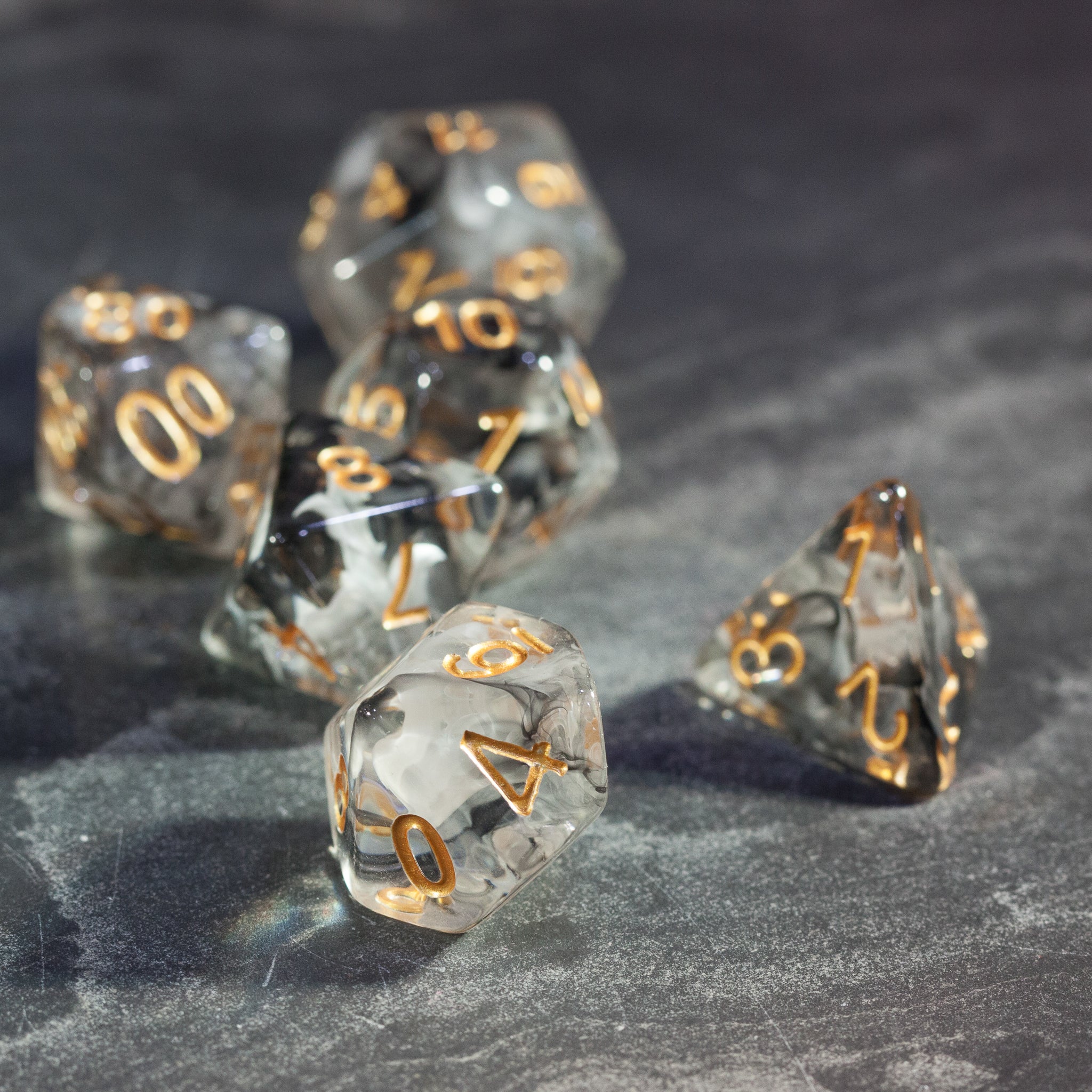 Black & White Smoke Dice Set - Black and white smoke marbled polyhedral dice set with gold numbering on dark surface.