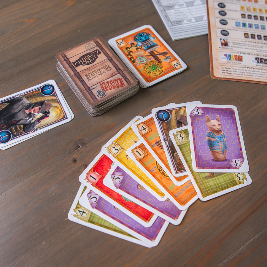 Antiquity Quest - Antiquity Quest board game cards spread out on wooden table featuring colorful, illustrated artifact images and character.
