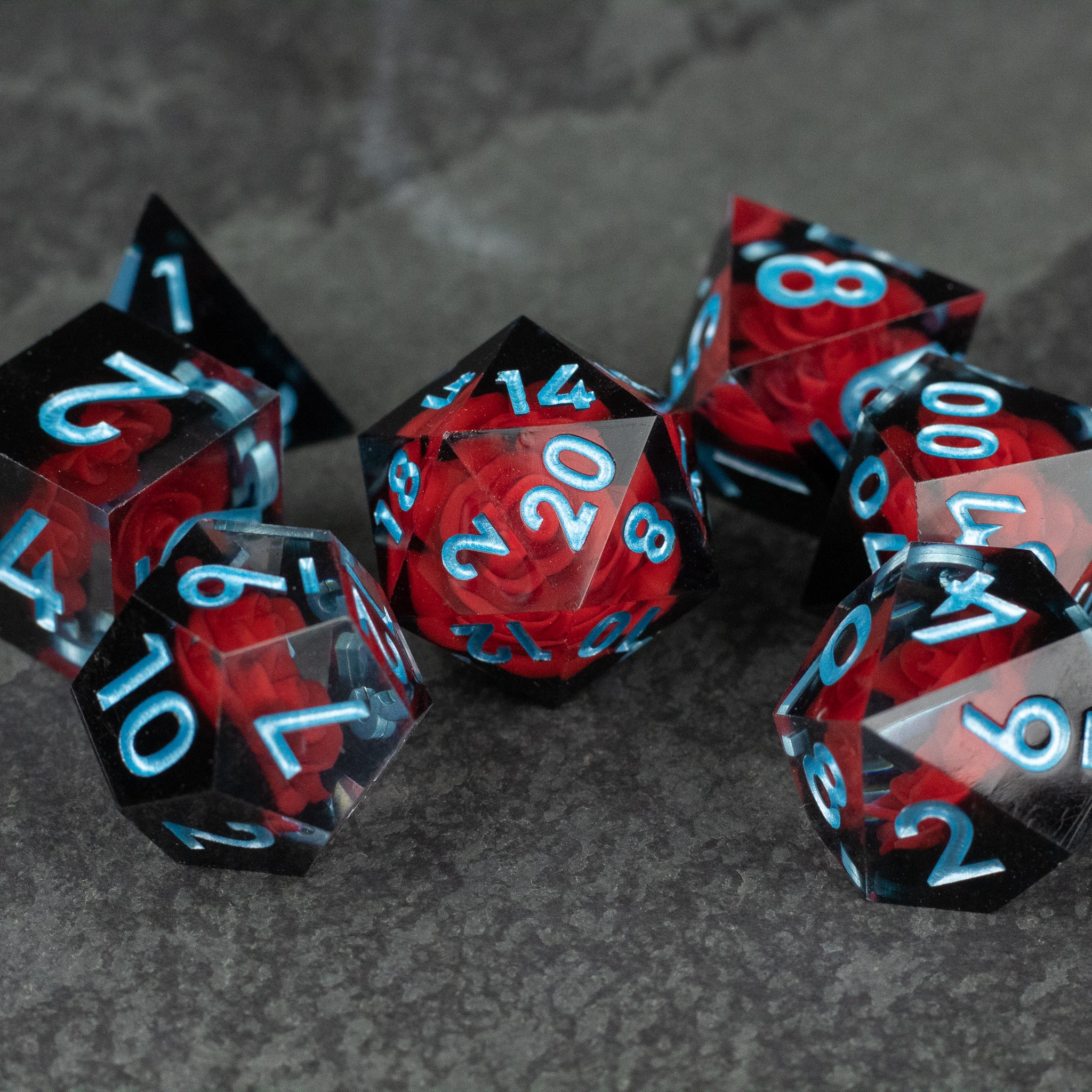 Cursed Rose Dice Set - Translucent red and black sharp-edged dice set with white numbers, including a d20, d12, d10, d8, d6, and d4.