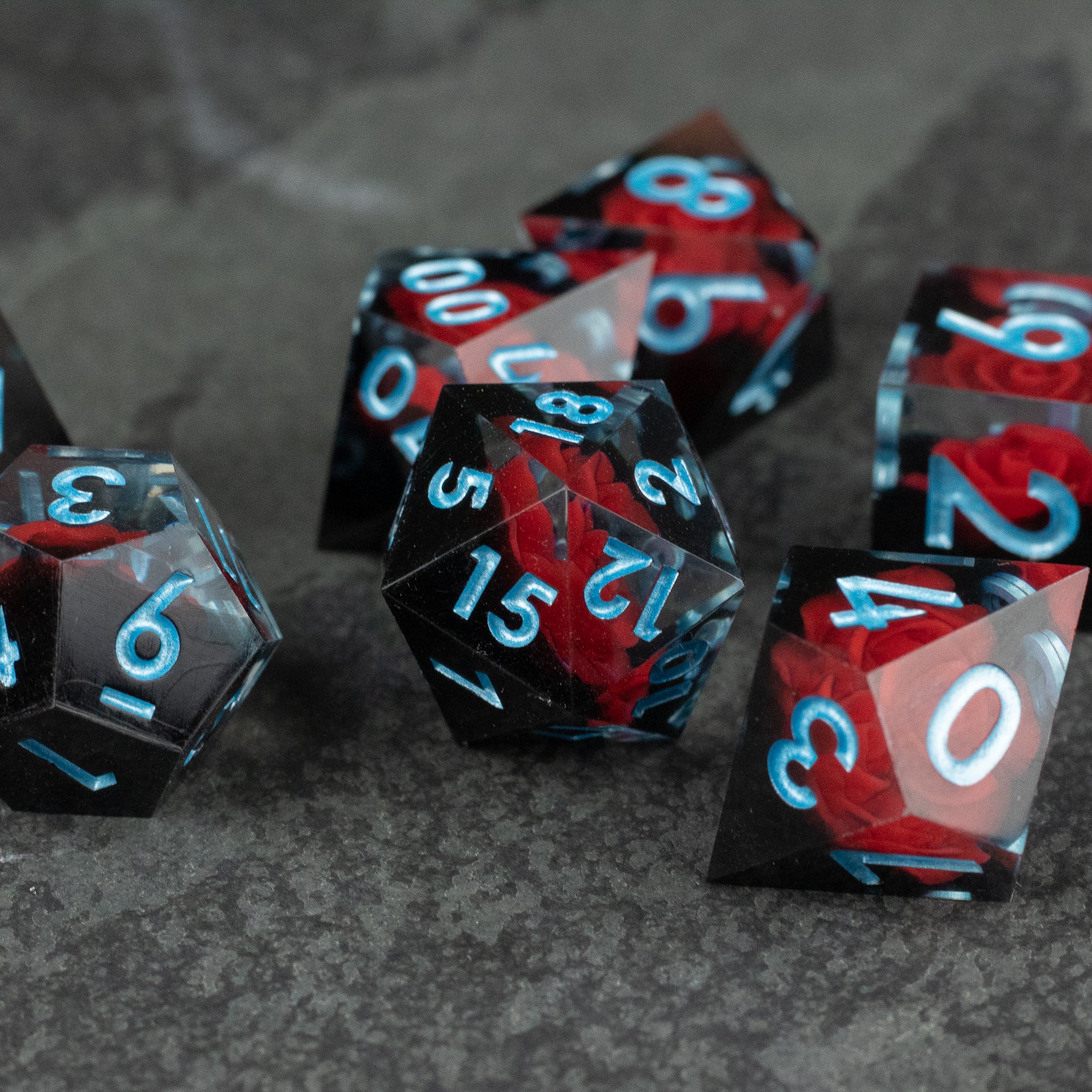 Cursed Rose Dice Set - Sharp-edged polyhedral dice set with smoky black and deep red swirls and blue numbers.