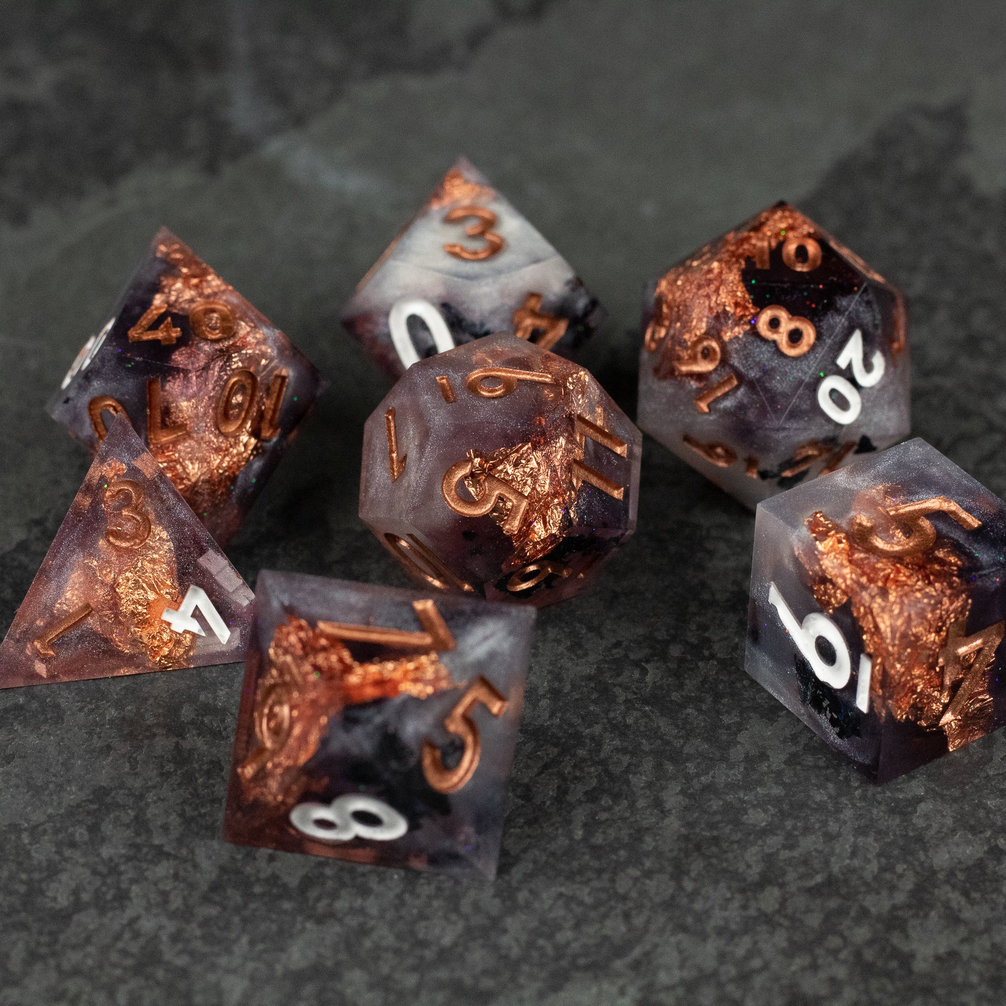 Lich King Dice Set - Set of seven sharp-edged polyhedral dice with dark translucent bodies and metallic copper inclusions, featuring white and.