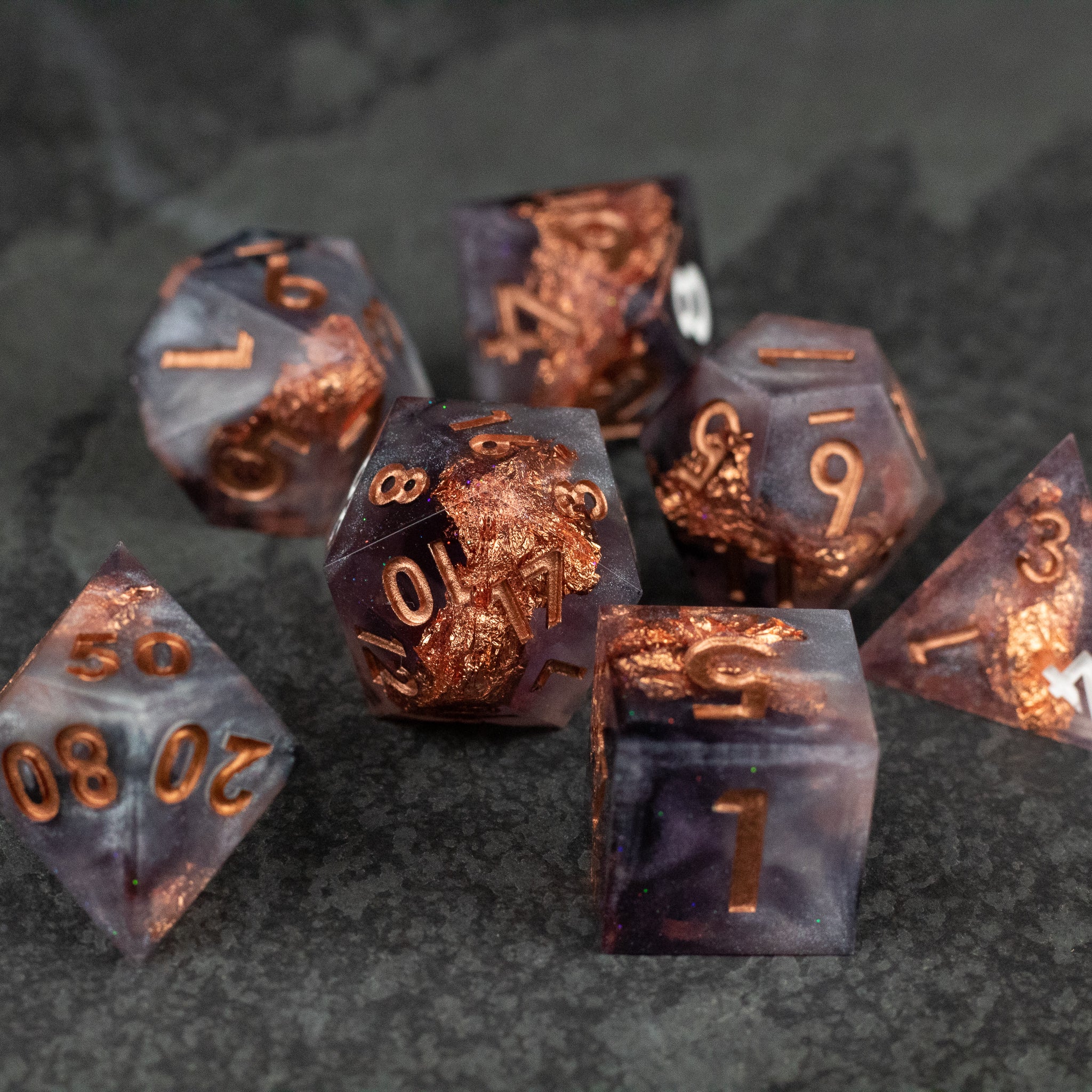 Lich King Dice Set - Seven dark purple translucent polyhedral dice with sharp edges and copper-colored numbering and intricate designs, including
