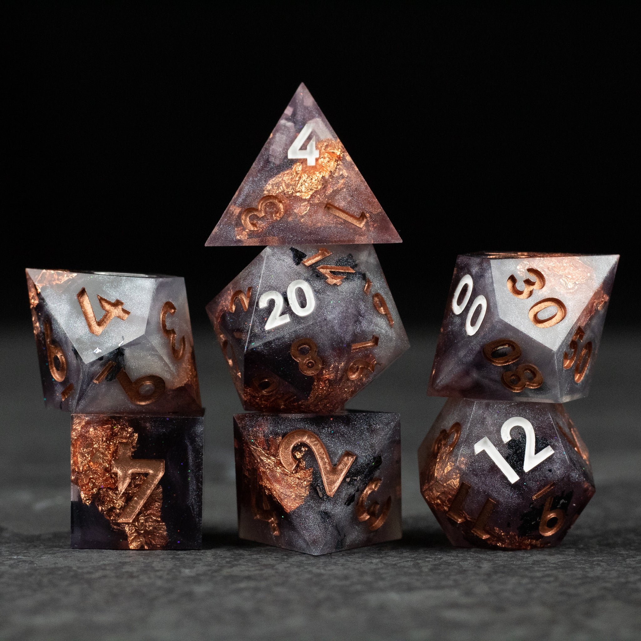 Lich King Dice Set - Seven black and copper sharp-edged dice with white numbers from the Lich King Dice Set arranged on a dark surface.