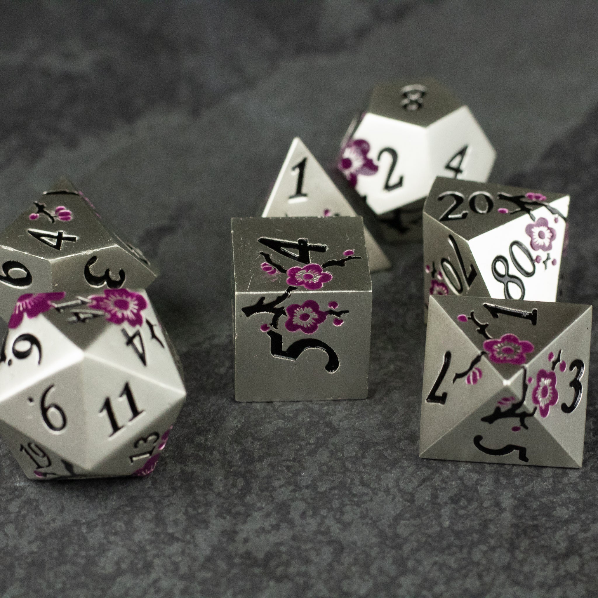 Silver & Maroon Metal Flower Dice - Set of silver metal dice with maroon floral engravings and black numbering on dark surface.