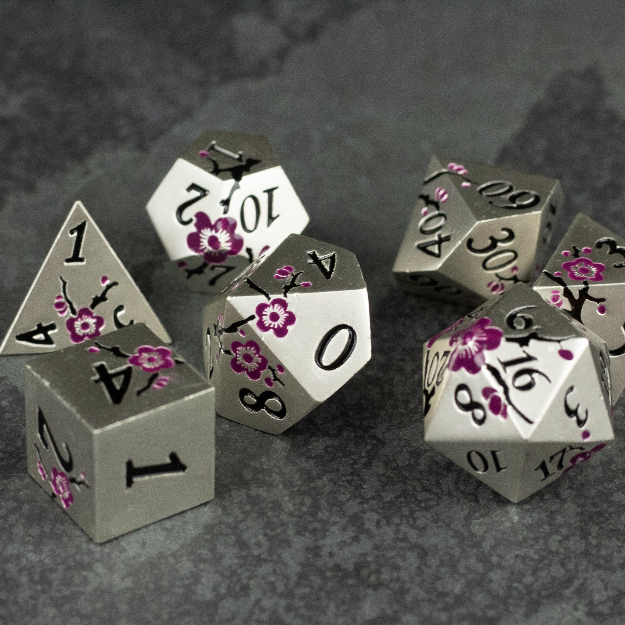 Silver & Maroon Metal Flower Dice - Set of silver metal polyhedral dice with maroon floral engravings and black numbering on a dark textured surface.