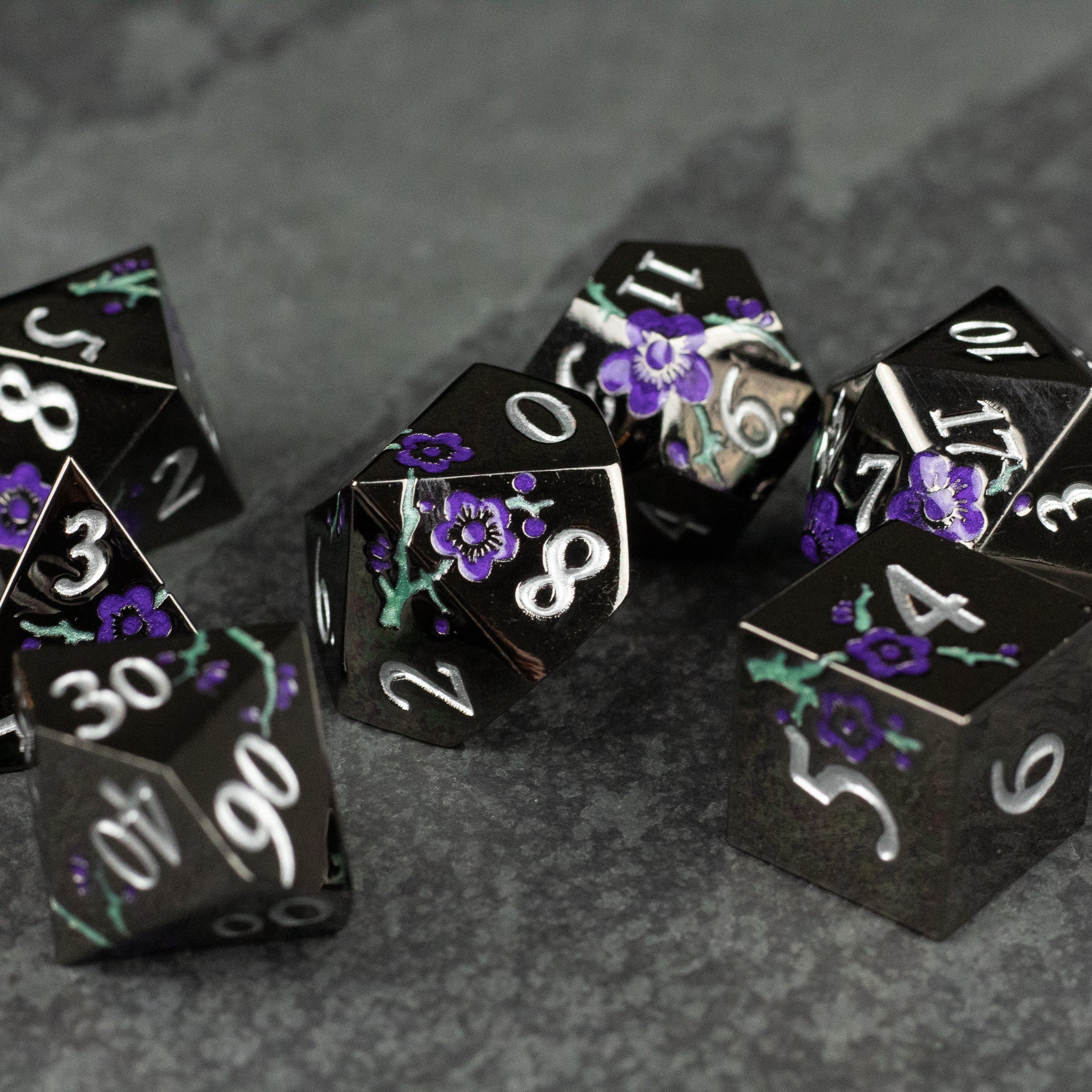 Black and Purple Metal Flower Dice - Set of black metal dice with white numbers and purple floral patterns on each face.