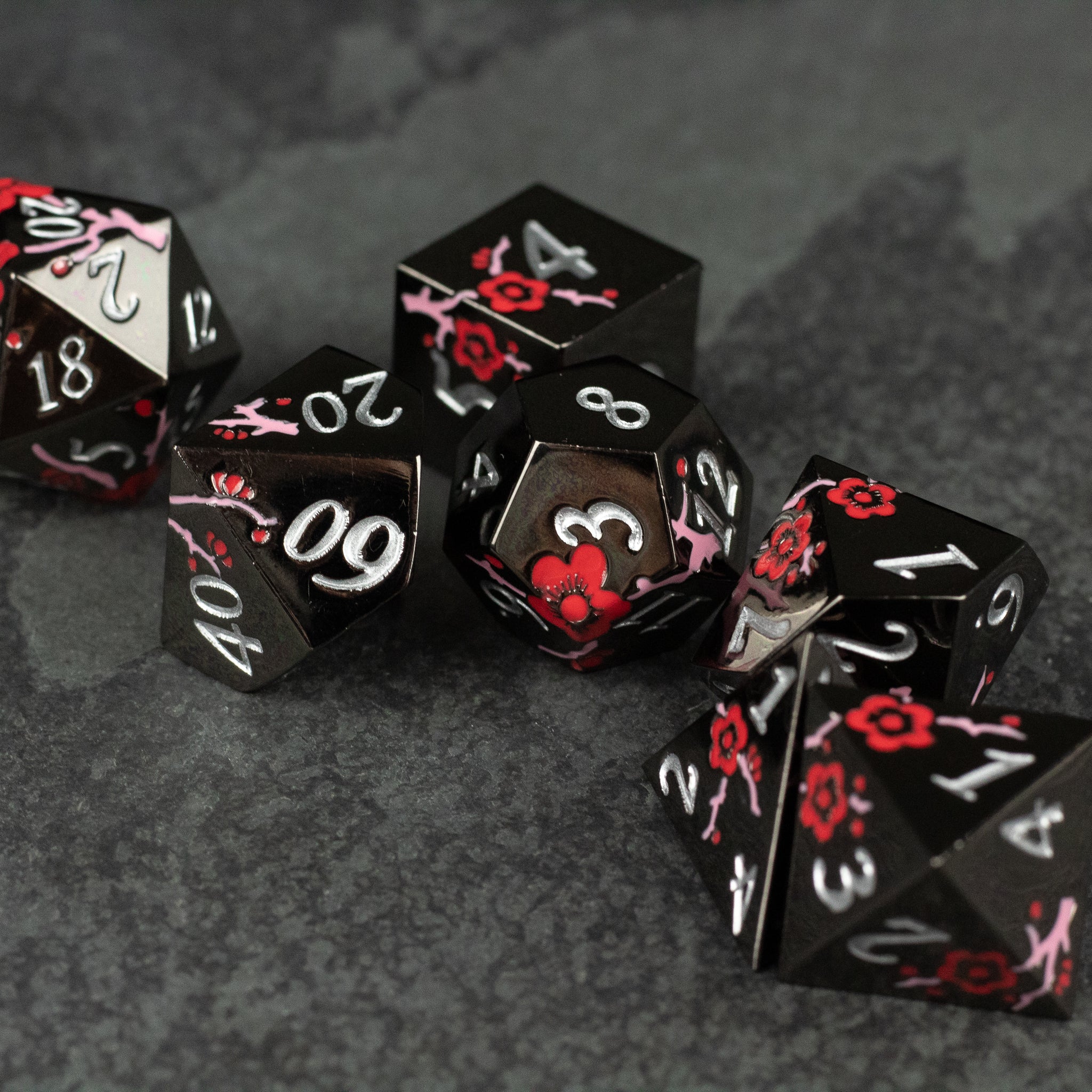 Black & Red Metal Flower Dice - Set of black metal dice with red floral designs and white numbers, including d20, d12, d10, d8, d6, and d4.