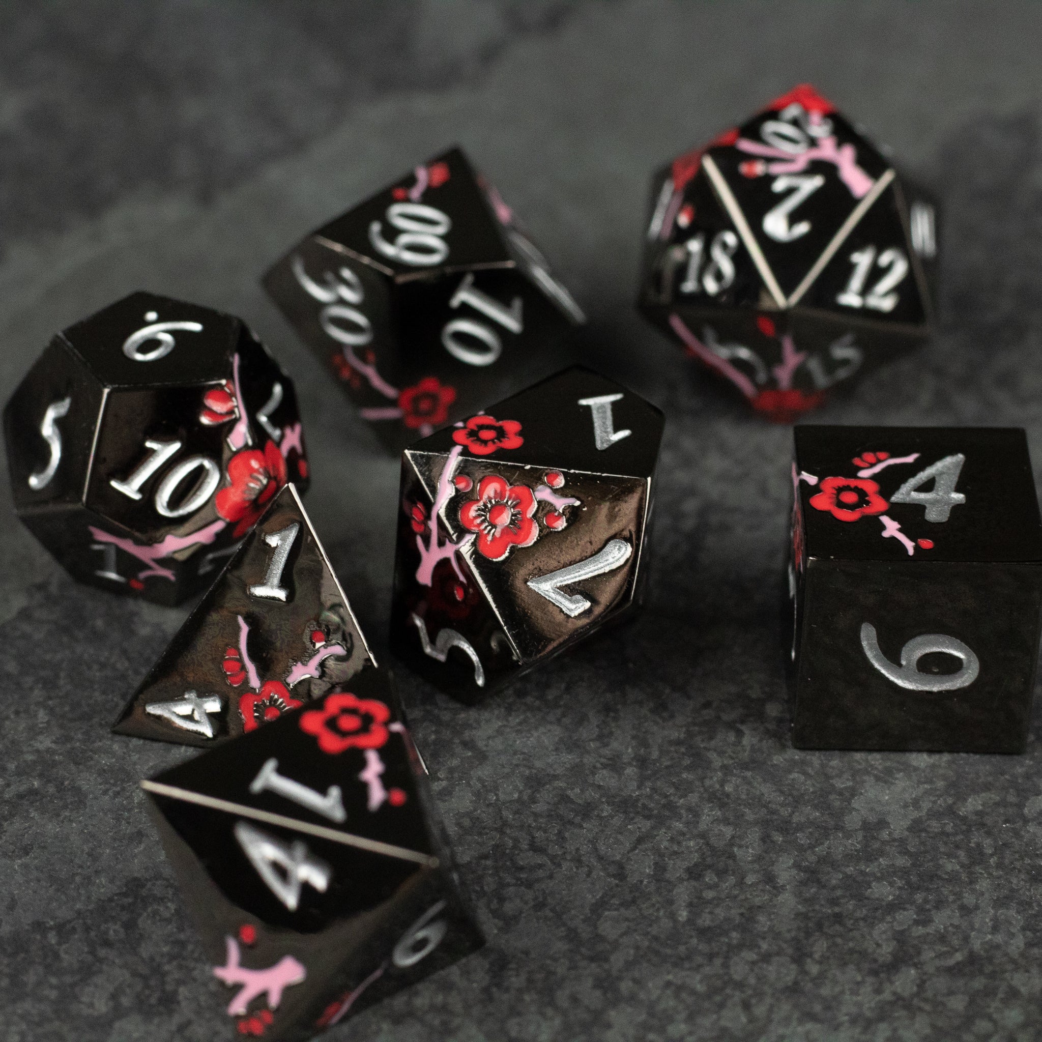 Black & Red Metal Flower Dice - Black metal polyhedral dice set with red floral engravings and white numbering.