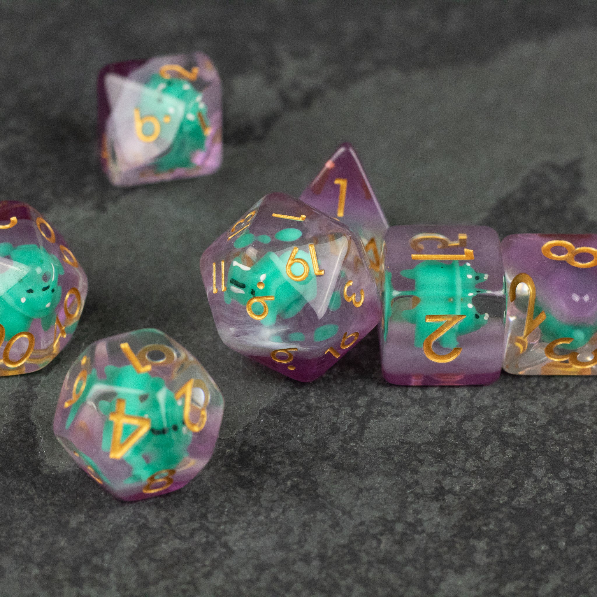 Green Triceratops Dice Set - Purple translucent polyhedral dice set with green triceratops figures inside and gold numbers.