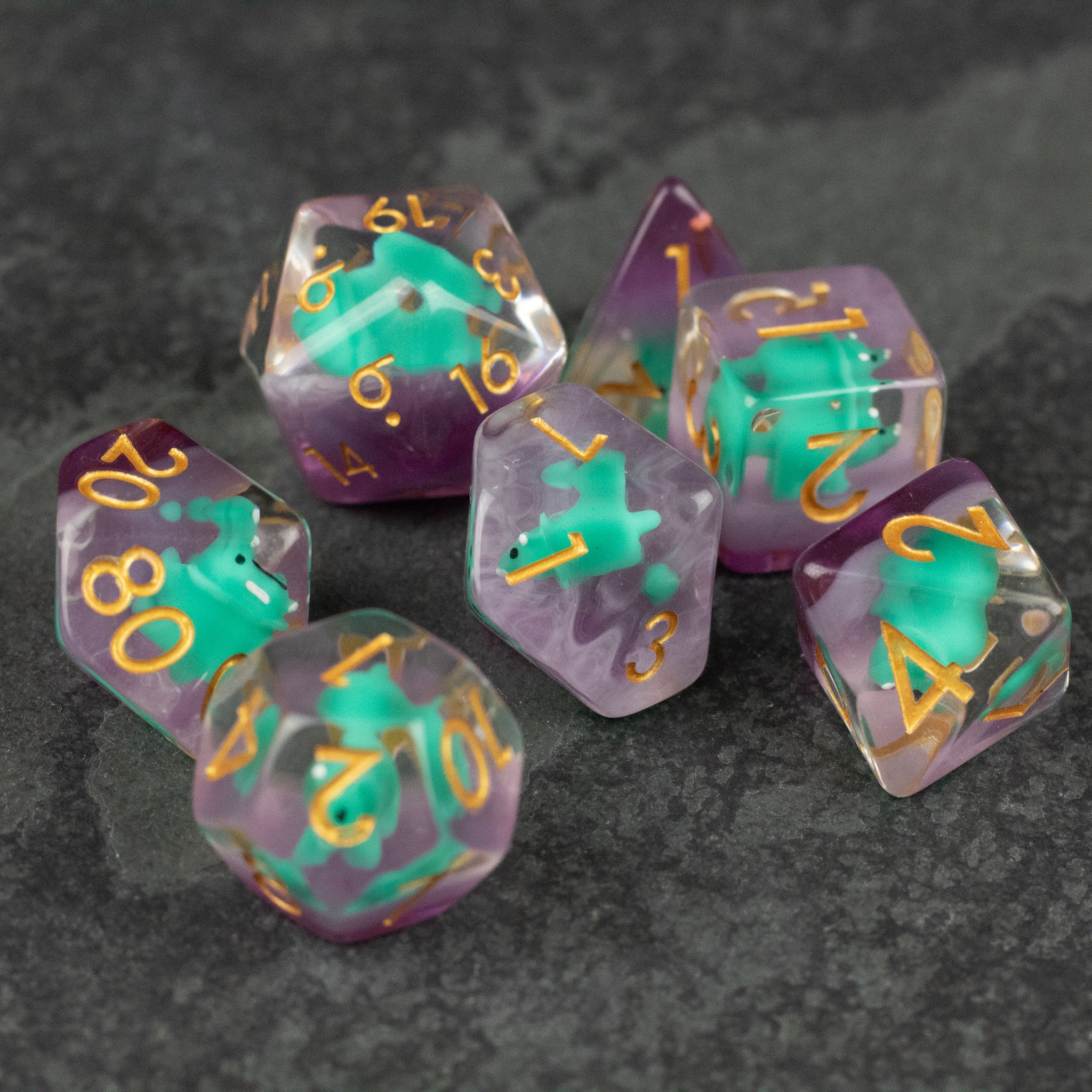 Green Triceratops Dice Set - Set of six translucent purple dice with embedded green triceratops figures and gold numbers.