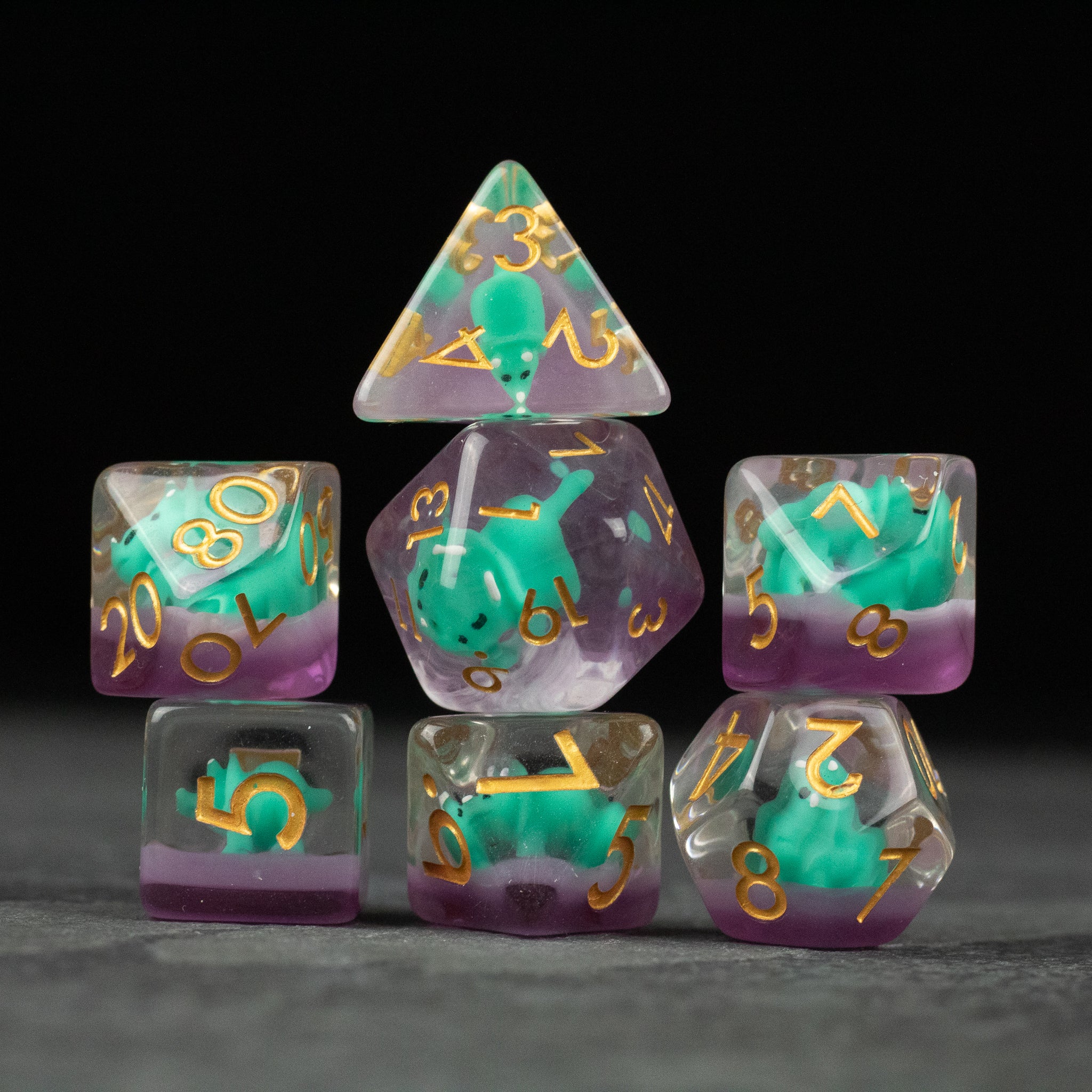 Green Triceratops Dice Set - Transparent purple polyhedral dice set with green triceratops figures inside and gold numbering.