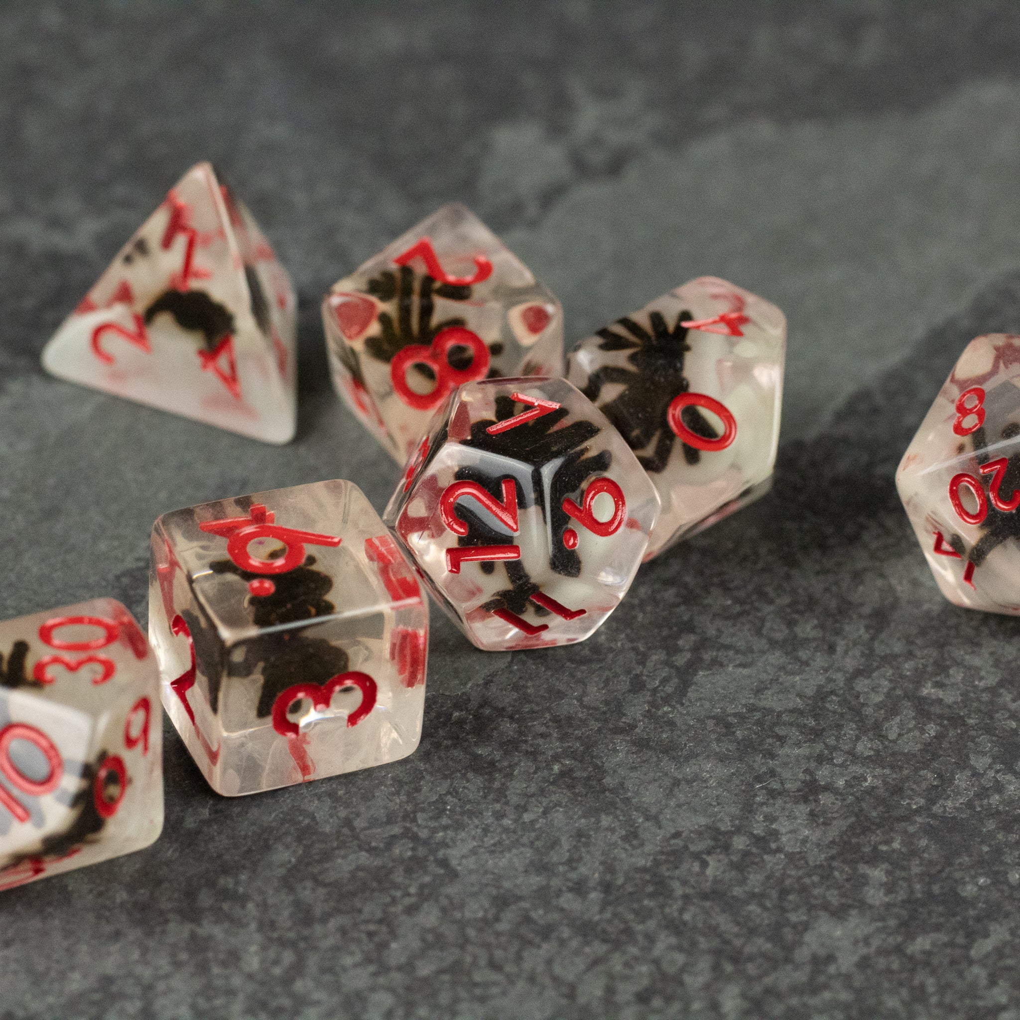 Black Spider Dice Set - White - Black transparent polyhedral dice set with white spider designs and red numbers, including d4, d6, d8, d10, d12, and d20.